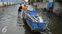 Sejumlah warga membawa ikan dengan gerobak melintasi banjir di Kawasan Muara Angke, Jakarta, Rabu (11/1). Banjir rob setiap laut pasang ini terjadi setelah tanggul laut jebol pada pertengahan tahun lalu. (Liputan6.com/Gempur M. Surya)