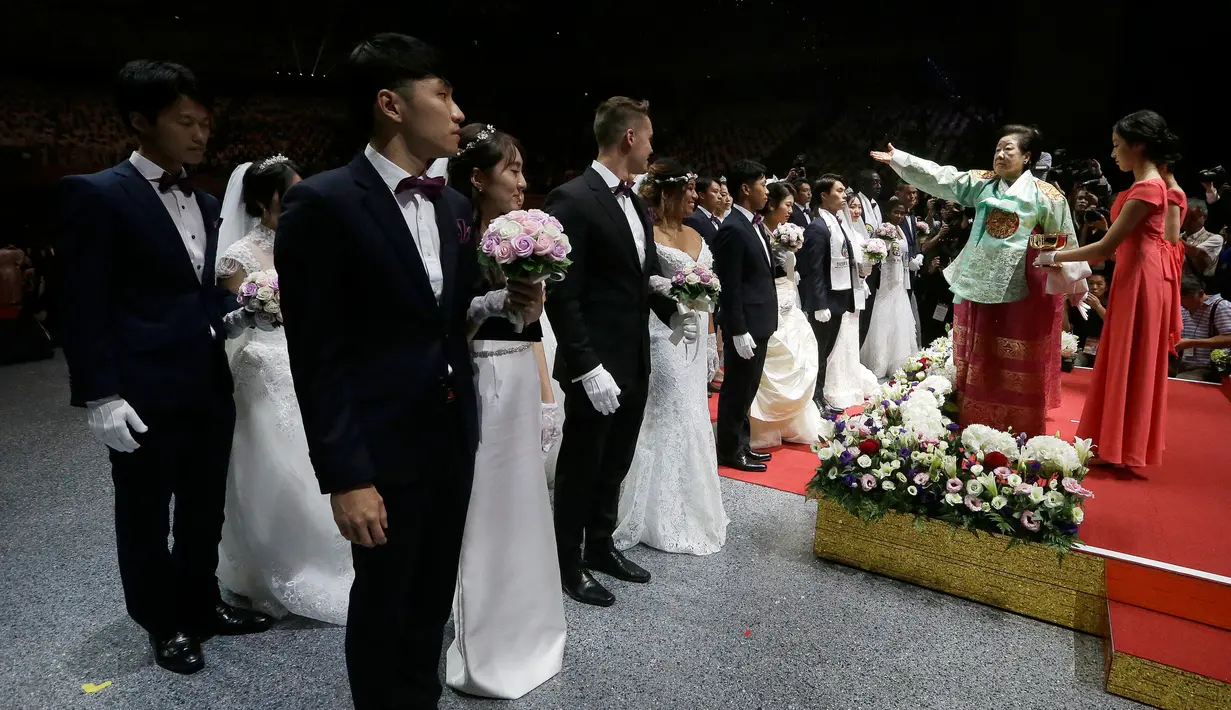 Istri pendiri Gereja Unifikasi almarhum Pdt. Sun Myung Moon, Hak Ja Han Moon (dua kanan) menyiramkan air suci untuk memberkati pasangan pengantin dalam pernikahan massal di Gapyeong, Korea Selatan, Senin (27/8). (AP Photo/Ahn Young-joon)