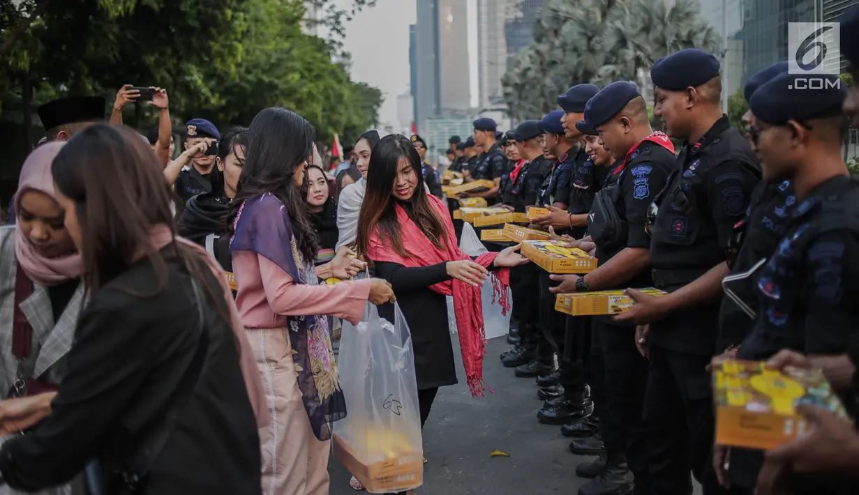 Peserta aksi yang tergabung dalam Mahasiswa dan Pemuda Relawan Cinta NKRI membagikan takjil ke anggota Polri yang bertugas di Gedung Bawaslu RI, Jakarta, Minggu (26/5). Aksi simpatik sebagai wujud apresiasi kepada anggota Polri-TNI yang menjaga keamanan aksi 22 Mei 2019. (Liputan6.com/Faizal Fanani)