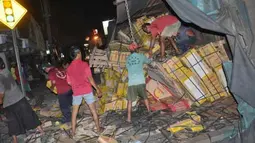 Sejumlah warga membantu mengangkat keramik saat truk gandeng terguling di jalur pantura, Tegal, Jateng, Jumat (30/3) malam. Truk pengangkut keramik terguling karena as roda patah mengakibatkan dua pengendara sepeda motor cedera tertimpa truk dan pantura sempat macet selama 5 jam. (Antara)