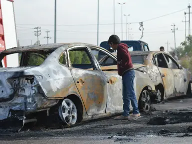 Seorang remaja melihat mobil yang hancur akibat bom di Ameriyat Falluja, Irak, Jumat (18/11). Mobil tersebut sengaja dijadikan bom yang diduga dilakukan oleh kelompok ISIS. (Reuters/Osamah Waheeb) 