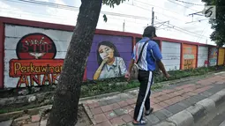 Pejalan kaki berjalan di depan mural bertema 'Tolak Kekerasan Perempuan dan Pelecehan Seksual' di Jatinegara, Jakarta, Senin (17/12). Mural tersebut dibuat untuk meningkatkan kesadaran akan ancaman bahaya pelecehan seksual. (Merdeka.com/Iqbal S. Nugroho)