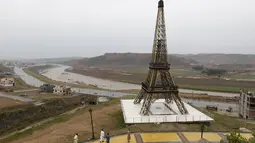 Warga melintasi replika Menara Eiffel yang berdiri di sebuah bukit di Kota Bahria, Pakistan, 16 Maret 2016. Replika dengan tinggi mencapai 80 meter itu diklaim sebagai tertinggi ketiga di dunia setelah yang ada di Paris dan China. (REUTERS/Caren Firouz)