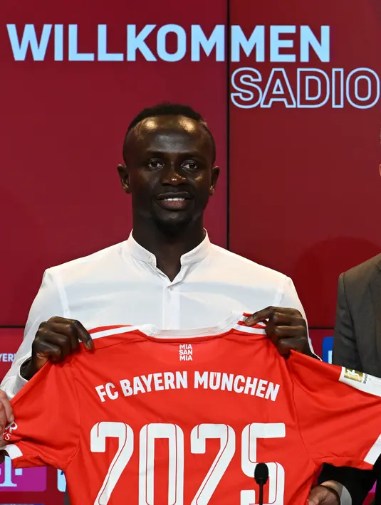 Penyerang baru Bayern Munchen, Sadio Mane berpose dengan jerseynya selama konferensi pers etelah ia menandatangani kontrak tiga tahun di Munich, Jerman selatan (22/6/2022). Bayern dilaporkan telah membayar biaya yang bisa naik menjadi 41 juta euro (USD 43 juta) untuk Mane. (AFP/CHRISTOF STACHE)