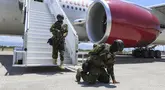 Petugas polisi Kenya yang tergabung dalam tim multinasional dukungan PBB berlutut di landasan sebagai ucapan terima kasih setelah mendarat di Bandara Internasional Toussaint Louverture di Port-au-Prince, Haiti, Selasa (16/7/2024).  (Foto AP/Odelyn Joseph)