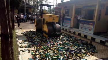 Sebuah alat berat, tengah memusnahkan ribuan botol miras berbagai jenis hasil razia menjelang natal dan tahun baru di Garut