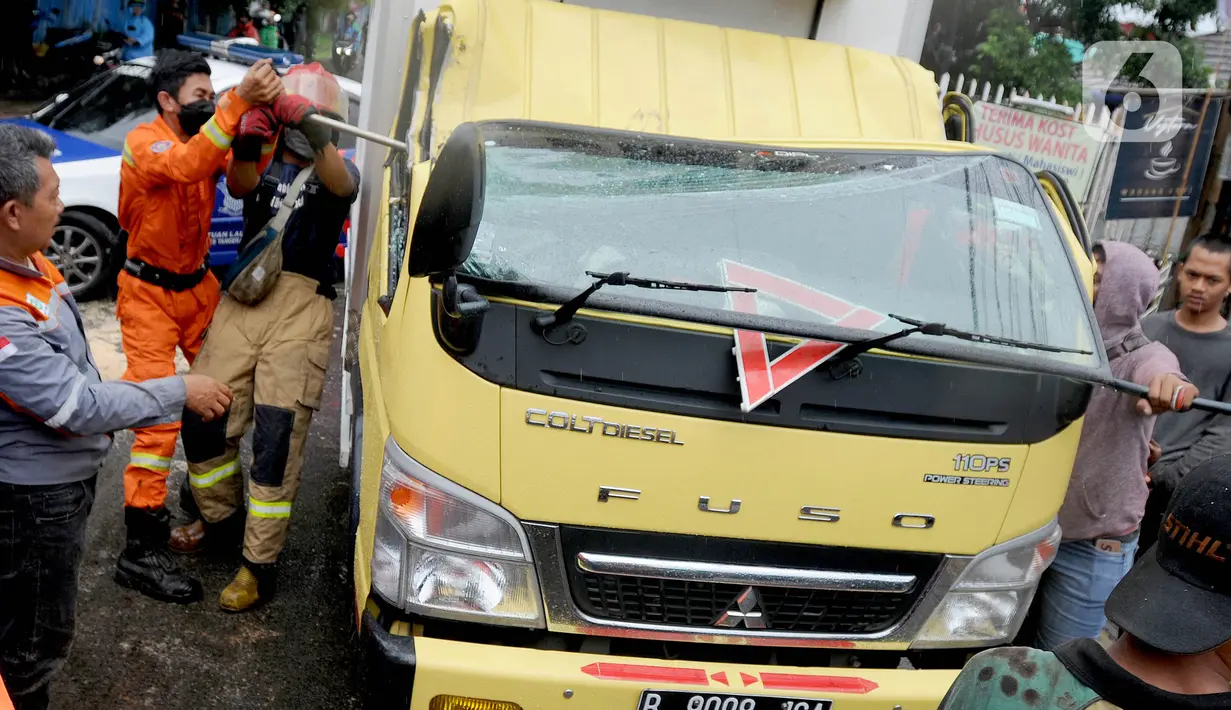 Petugas mengevakuasi truk boks yang rusak parah akibat tertimpa pohon tumbang di Jalan Padjajaran, Kota Tangerang Selatan, Banten, Sabtu (5/3/2022). Dua unit kendaraan dan dua pengendara motor yang sedang melintas tertimpa pohon tumbang saat angin kencang melanda Jabotabek. (merdeka.com/Arie Basuki)
