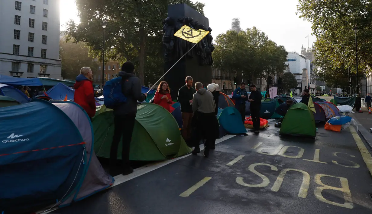 Aktivis iklim mengibarkan bendera ketika mereka berkemah di Whitehall, London, Inggris, Selasa (8/10/2019). Gerakan ini termasuk dalam pemberontakan internasional yang juga berlangsung di beberapa negara, seperti Australia dan Belanda. (AP Photo/Alastair Grant)