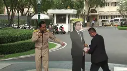 PM Thailand, Prayuth Chan-o-cha dalam konferensi pers saat pengawalnya memasang replika karton bergambar dirinya di Bangkok, Senin (8/1). PM Prayuth kemudian meninggalkan tempat konferensi pers, sementara replikanya berdiri di sana. (TPBS via AP)