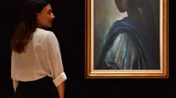 Karyawan rumah lelang Bonhams berdiri dekat lukisan seorang putri Nigeria bernama Tutu di London pada 7 Februari 2018. Mona Lisa dari Afrika itu sempat hilang bertahun-tahun sebelum ditemukan di apartemen London belum lama ini. (BEN STANSALL/AFP)