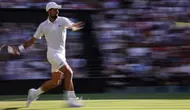 Petenis Serbia, Novak Djokovic, melakukan pengembalian forehand ke arah petenis Italia, Jannik Sinner, dalam pertandingan semifinal tunggal putra pada hari ke-12 Kejuaraan Wimbledon 2025 di All England Lawn Tennis and Croquet Club di Wimbledon, London barat daya, pada 11 Juli 2025. (HENRY NICHOLLS/AFP)