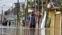 Seorang pria berjalan melalui jalan yang banjir di Bekasi, Jawa Barat, Kamis (17/2/2022). Hujan deras yang dikombinasikan dengan perencanaan pembuangan limbah kota yang buruk sering menyebabkan banjir besar. (AP Photo/Achmad Ibrahim)