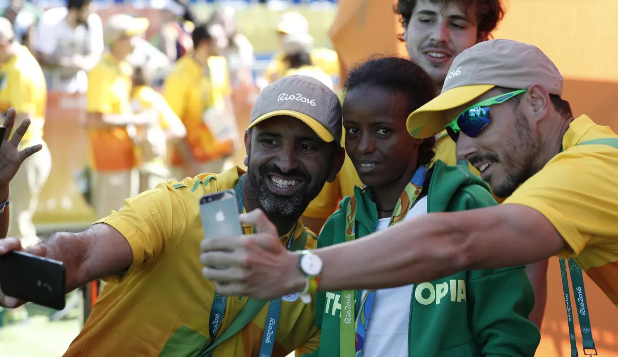 Atlet Ethiopia peraih medali perunggu, Mare Dibaba (tengah) berfoto bersama relawan usai turun dari atas podium cabang lari maraton putri Olimpiade 2016 di Rio de Janeiro, 14 Agustus 2016. (AFP PHOTO/Adrian Dennis)