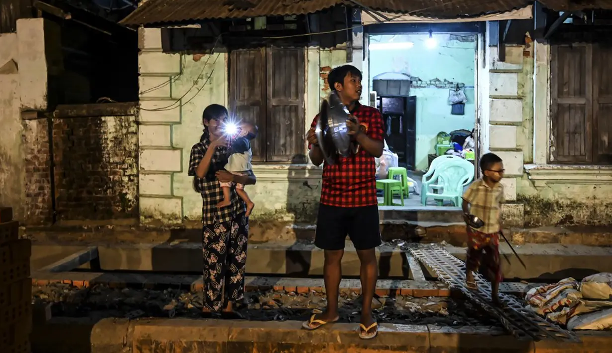 Orang-orang membuat keributan dengan memukul-mukul panci setelah seruan untuk protes keluar di media sosial di Yangon, Myanmar, 3 Februari 2021. Kudeta militer Myanmar terus memicu protes warga dengan membunyikan klakson mobil, menyalakan lampu ponsel, dan memukul-mukul panci. (STR/AFP)
