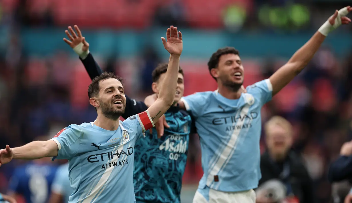 Pemain Manchester City, Benardo Silva (kiri), Phil Foden (tengah) dan Matheus Nunes (kanan) merayakan usai meraih gelar Piala FA  setelah mengalahkan Chelsea dengan skor 1-0 di partai final di Wembley Stadium hari Sabtu (16/05/2026) malam WIB. (AP Photo/Richard Pelham)