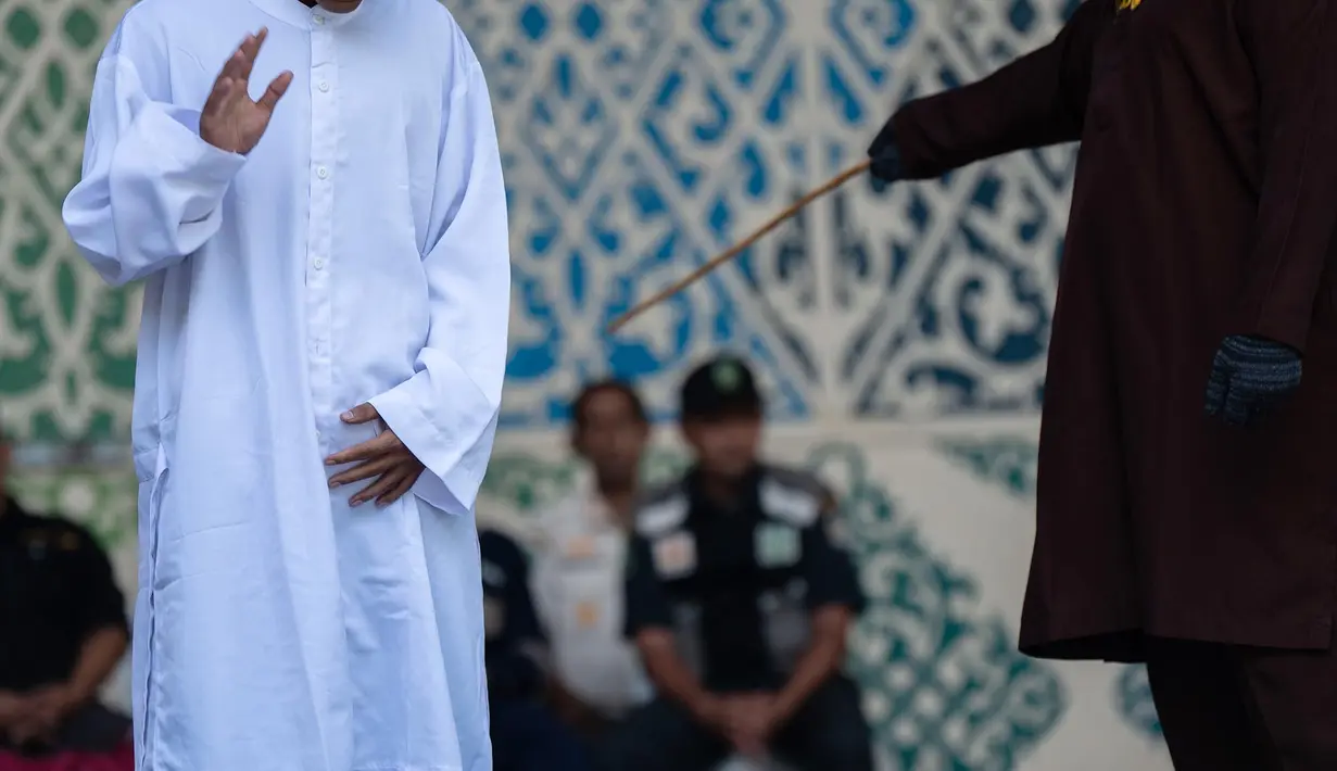 algojo mengeksekusi cambuk terhadap terpidana pelanggar hukum syariat Islam, diantaranya karena mencium seorang wanita saat siaran langsung TikTok, menjalani hukuman cambuk di Taman Bustanussalatin, Banda Aceh, Aceh, Kamis (2/7/2026). (AP Photo/Reza Saifullah)