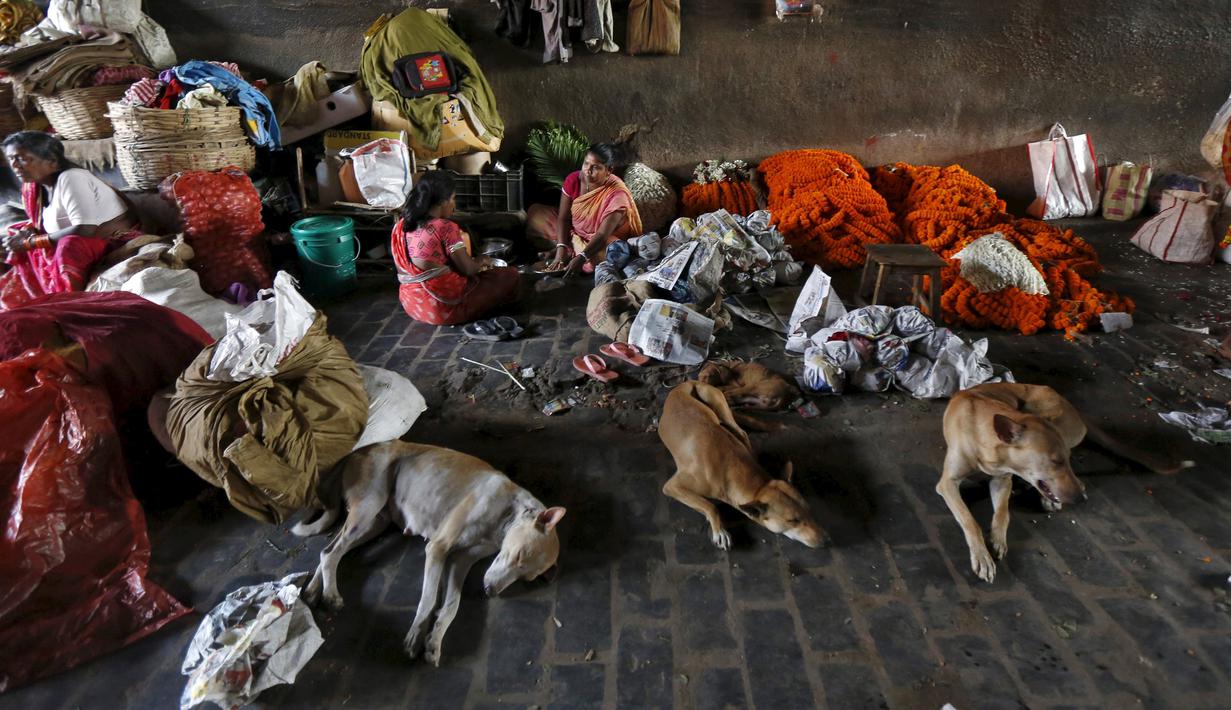 Perempuan India menjual karangan bunga di sebuah jembatan di Kolkata, 11 Maret 2016. Beberapa orang di Kolkata bekerja sebagai penjual pakaian bekas atau pengemudi becak dan mereka terlalu miskin untuk membeli rumah. (REUTERS/Rupak De Chowdhuri)