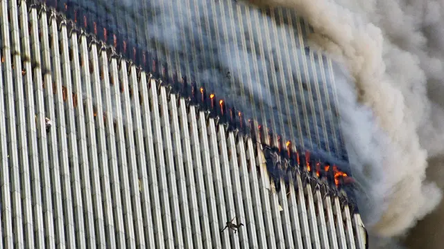 Seseorang jatuh dari Menara Utara WTC, sementara asap dan api mengepul dari gedung (AP Photos/Richard Drew)
