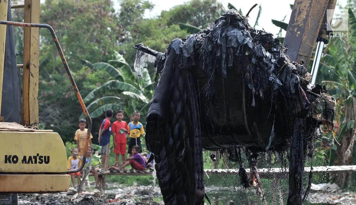 Anak-anak menyaksikan pengerukan sampah Kali Pisang Batu, Tarumajaya, Bekasi, Jawa Barat, Rabu (9/1). Petugas DLH Kabupaten Bekasi mulai membersihkan sampah setelah fenomena tersebut ramai diberitakan di media sosial. (Merdeka.com/Iqbal S. Nugroho)