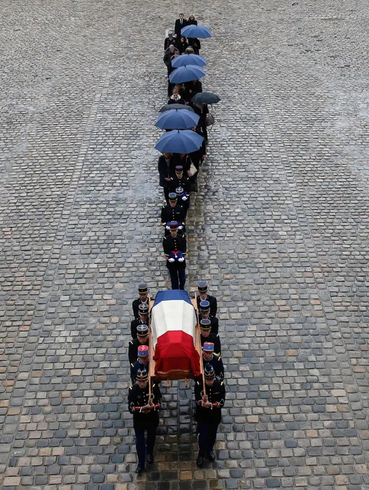 Anggota kepolisian Prancis menggotong peti mati Letnan Kolonel Arnaud Beltrame dalam upacara pemakaman nasional di Hotel des Invalides, Paris, Rabu (28/3). Meski berlangsung khidmat, namun hujan deras sempat mengguyur sepanjang upacara (AP/Christophe Ena)