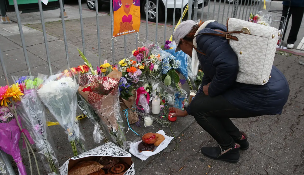 Seorang wanita menaruh lilin di tempat peringatan Gudang Terbakar di California, AS, Senin (5/12). Warga bersimpati atas peristiwa kebakaran gudang dengan memberikan bunga dan benda-benda lainnya. (REUTERS / Lucy Nicholson)