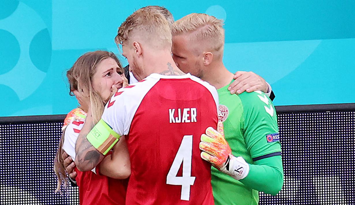 Kapten Denmark, Simon Kjaer dan Kasper Schmeichel, berusaha menenangkan istri Christian Eriksen, Sabrina Kvist Jensen, usai kolaps saat melawan Finlandia pada laga Piala Eropa di Stadion Parken (12/6/2021). (AFP/Wlofgang Ratttay)