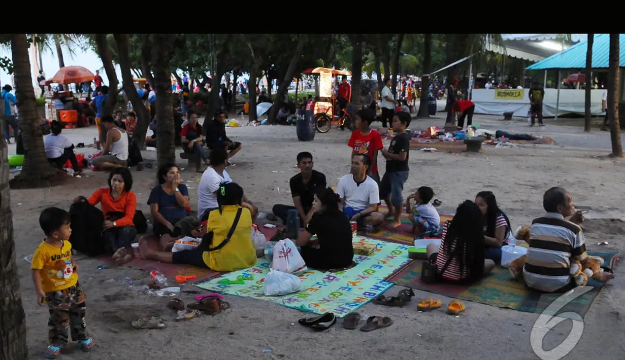 Para pengunjung bersantai bersama keluarga mereka di pinggir pantai Ancol di hari pertama Idul Fitri, Jakarta, Senin (28/7/2014) (Liputan6.com/Andrian M Tunay)
