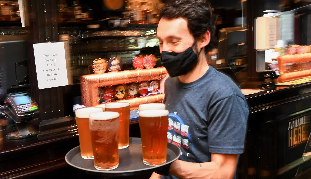 Seorang pelanggan membawa nampan bir ke mejanya di sebuah pub di Melbourne, Australia, Jumat (22/10/2021). Para pemilik bar, restoran, dan salon menyambut kembali para pelanggan sekaligus berharap bisnis mereka akan kembali hidup pascalockdown. (William WEST/AFP)
