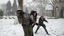 Warga bermain lempar bola salju di dekat masjid Suleymaniye di Istanbul pada 23 Januari 2022. Badai musim dingin dan hujan salju tetap berlaku di sebagian besar wilayah Turki, menyebabkan penutupan jalan antara ribuan desa dan kota di banyak daerah.  (Yasin AKGUL / AFP)