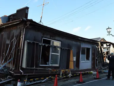 Seorang wisatawan mengamati sebuah rumah kosong di Namie, Prefektur Fukushima, 11 Februari 2016. Lima tahun pasca bencana nuklir yang dipicu gempa dan tsunami Jepang, semakin banyak wisatawan yang bergabung dengan tur Fukushima (AFP PHOTO/Toru Yamanaka)