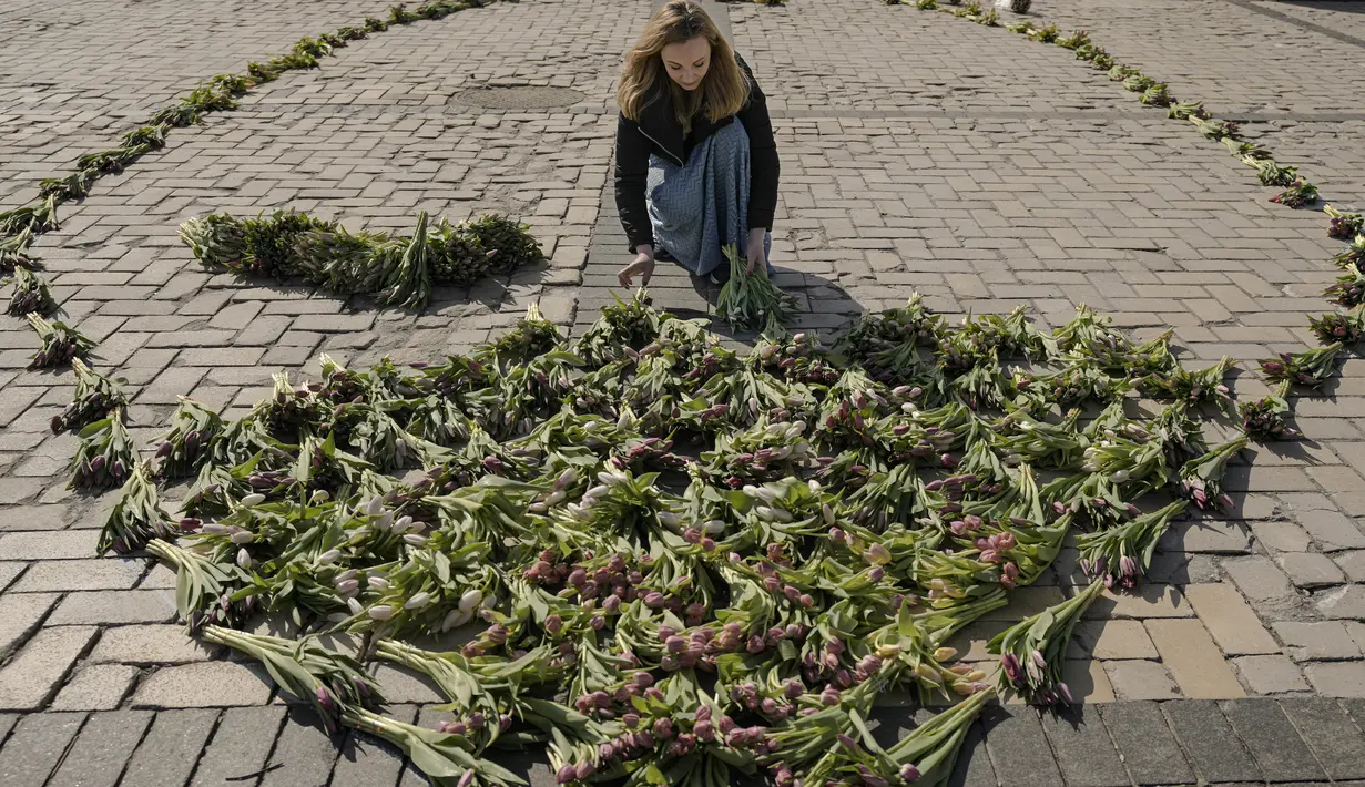 Seorang wanita menata bunga tulip di alun-alun Sophia di Kiev, Ukraina (18/3/2022). Warga Kiev turun ke alun-alun pusat untuk menata sekitar 1,5 juta bunga tulip bentuk lambang negara dalam pertunjukan normal yang menantang saat pasukan Rusia mengepung dan mengebom kota. (AP Photo/Vadim Ghirda)