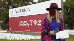 Seniman Suzanne Brennan Firstenberg berdiri dekat instalasi seni berupa bendera putih yang ditanam untuk mengenang warga Amerika yang meninggal karena COVID-19 di dekat Stadion RFK, Washington, Selasa (27/10/2020). Setiap bendera mewakili satu nyawa yang hilang akibat Covid-19. (AP/Patrick Semansky)