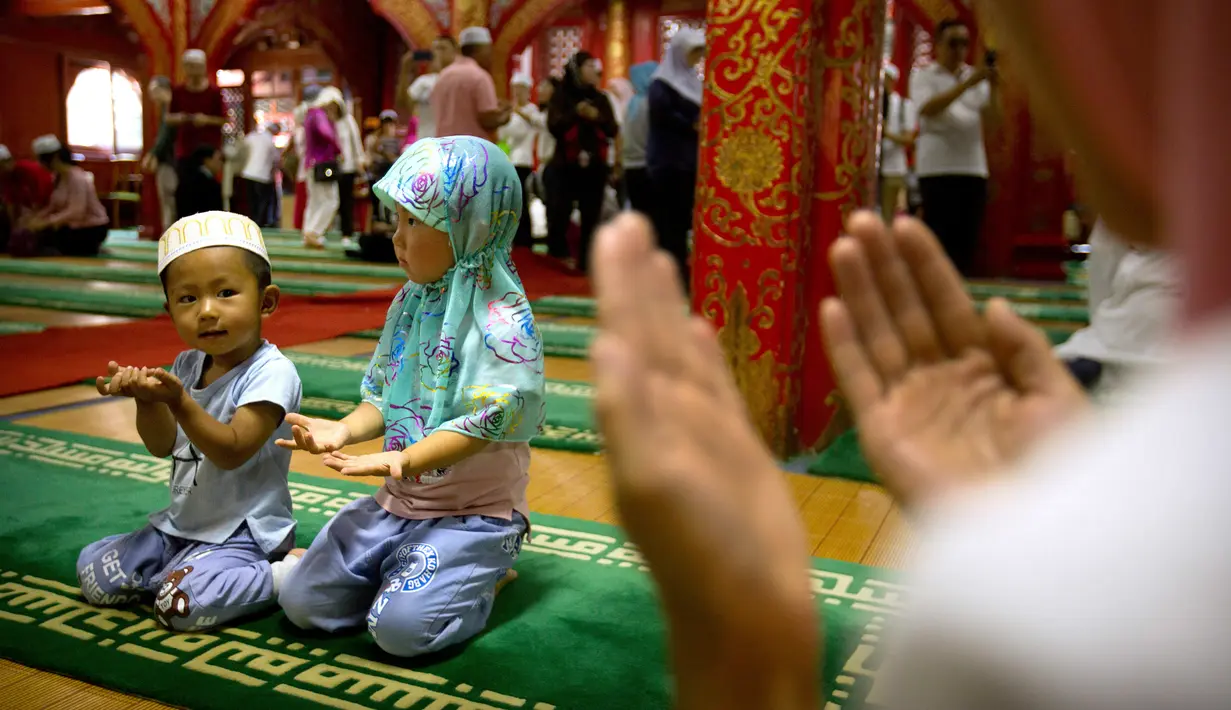 Dua orang anak berdoa usai mengikuti salat Idul Fitri, di masjid Niujie, Beijing, 26 Juni 2017. Masjid Niujie merupakan Masjid bersejarah di Kota Beijing dan mnjadi tempat ibadah masyarakat muslim. (AP Photo/Mark Schiefelbein)