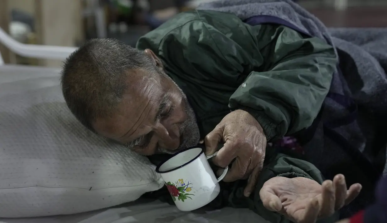 Victor Regis Ramirez, yang diusir dari rumah kontrakannya, minum dari cangkir saat berbaring di tempat tidur di tempat penampungan tunawisma di Asuncion, Paraguay, Jumat (2/7/2021). Menurut direktur National Emergency Office jumlah tunawisma telah meningkat di tengah pandemi. (Ap Photo/Jorge Saenz)