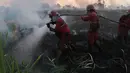 Petugas pemadam kebakaran membawa peralatan mereka saat berupaya memadamkan kebakaran lahan gambut di Palembang, Sumatra Selatan, Indonesia, Selasa, 11 Agustus 2026. (Foto AP/Muhammad Hatta)
