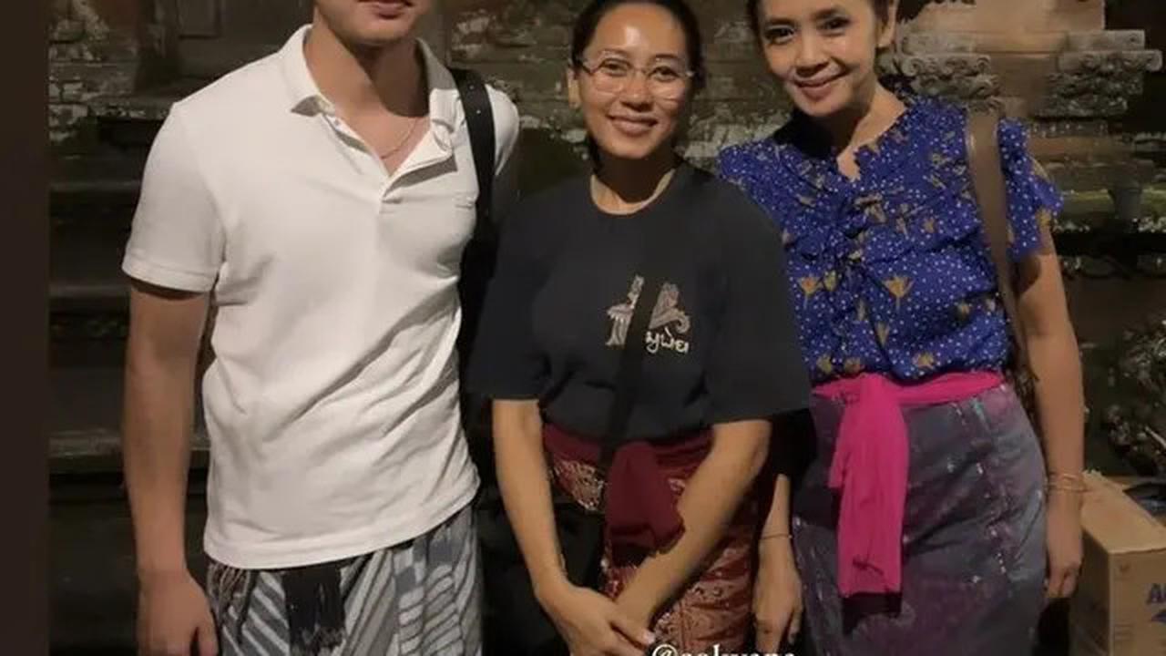 Nicholas Saputra tampil dalam polo shirt putih dan kain abu-abu bercorak.