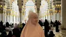 Sementara itu pada potret terakhir di dalam masjid, ia mengenakan busana syari berwarna peach pastel yang memancarkan aura feminin dan lembut. Warna tersebut memantulkan cahaya interior dengan cantik sehingga wajahnya terlihat glowing alami. Model khimar yang rapi dengan detail minimal membuat tampilannya semakin dewasa dan anggun.  [@rklopper].