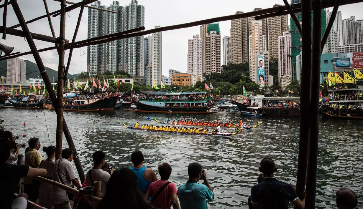 Para penonton melihat sejumlah tim bersaing dalam peringatan tahunan Tuen Ng atau Festival Perahu Naga di Hong Kong, Kamis (9/6). Perahu yang berukuran 10 meter itu diukir berbentuk kepala naga dan ekornya. (Anthony WALLACE/AFP)