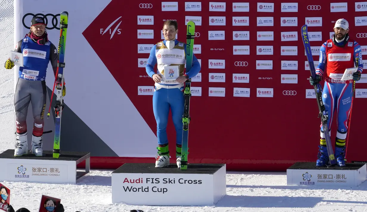 Pemenang Sergey Ridzick dari Rusia (tengah) dan Brady Leman dari Kanada serta Bastien Midol dari Prancis saat upacara penghargaan nomor lintas ski putra selama uji coba Olimpiade Musim Dingin 2022 di Genting Resort Secret Garden di Zhangjiakou, China, Sabtu (27/11/2021). (AP Photo/Mark Schiefelbein)