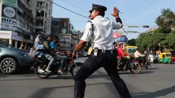 Seorang polisi lalu lintas India, Ranjeet Singh arus kendaraan bermotor di persimpangan yang sibuk di Indore pada 18 November 2019. Singh yang berusia 40 tahun ini selama sepuluh tahun terakhir mengatur lalu lintas sambil menarikan gaya ikonik milik Michael Jackson 'moonwalk.' (AP/Aijaz Rahi)