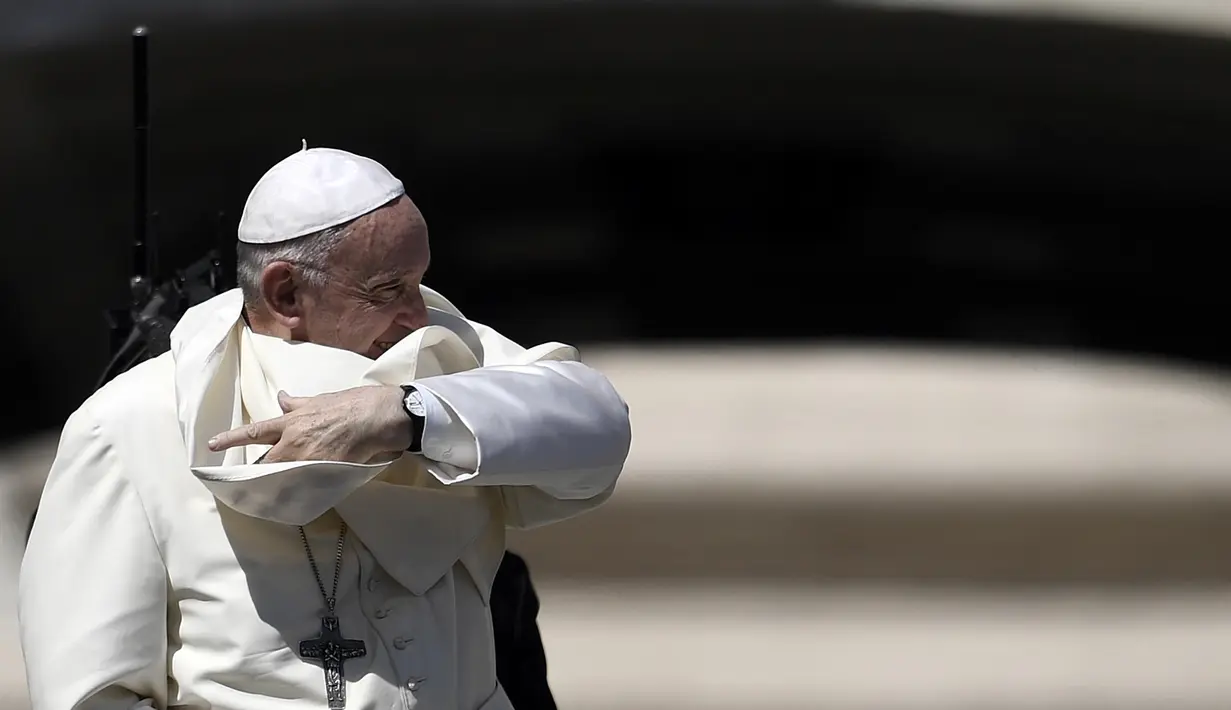 Paus Fransiskus menahan jubahnya yang diterpa angin saat memberkati umat setelah misa pada pertemuan dengan para pemuda di Lapangan Santo Petrus, Vatikan, Minggu (12/8). Tiupan angin membuat wajah Paus tertutup jubah. (AFP PHOTO / FILIPPO MONTEFORTE)