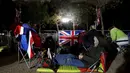 Anggota masyarakat beristirahat di The Mall di London, Minggu, 18 September 2022, jelang pemakaman Ratu Elizabeth II pada Senin (19/9). (David Davies/PA via AP)