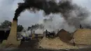 Asap mengepul dari cerobong asap saat pekerja menyiapkan gula merah di pinggiran Bareilly, India, Selasa (23/3/2021).  Jaggery adalah gula tradisional yang tidak dimurnikan yang dikonsumsi di banyak bagian Asia, terbuat dari molase tebu dan nira kurma. (AP Photo/Rajesh Kumar Singh)