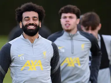 Pemain Liverpool Mohamed Salah (kiri) tertawa saat sesi latihan bersama rekan setimnya di tempat latihan mereka di Kirkby, Inggris, 6 Desember 2021. Liverpool akan menghadapi AC Milan pada pertandingan Grup B Liga Champions. (Oli SCARFF/AFP)