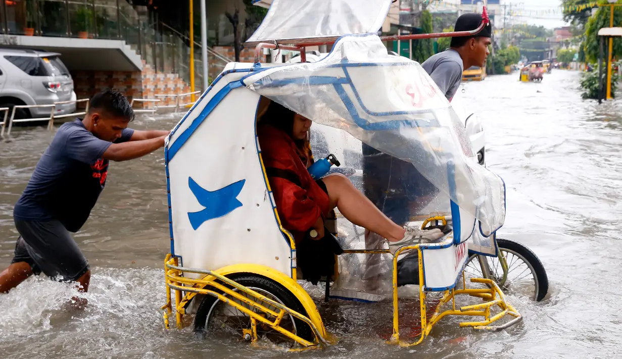 Seorang komuter mengangkat kakinya agar tetap kering saat ia menaiki becak roda tiga di Metropolitan Manila, Filipina, Jumat (20/7). Banjir menyebabkan siswa sekolah diliburkan selama tiga hari. (AP Photo/Bullit Marquez)