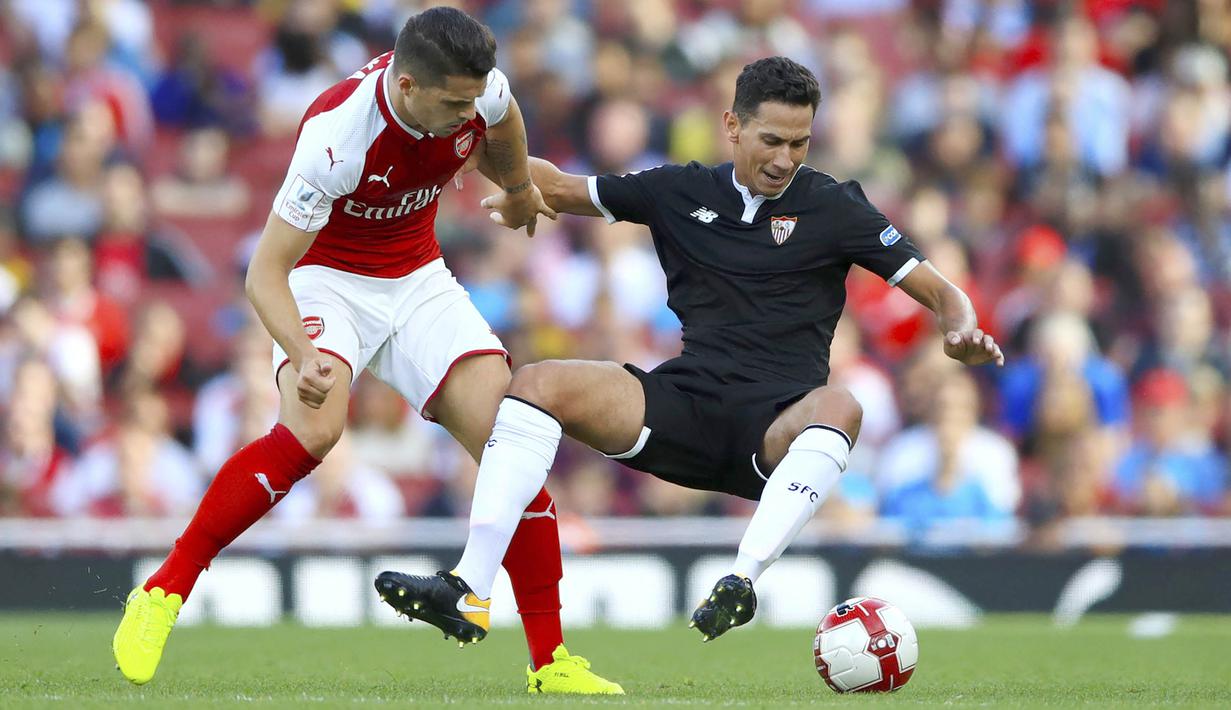 Gelandang Arsenal, Granit Xhaka, berebut bola dengan gelandang Sevilla, Paulo Henrique Ganso pada laga turnamen Piala Emirates yang berlangsung di Stadion Emirates, Minggu (30/7/2017). Arsenal takluk 1-2 dari Sevilla. (AP/John Walton)
