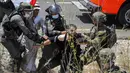 Tentara Israel mengamankan seorang pengunjuk rasa Palestina yang memprotes pembukaan lahan untuk permukiman Israel di dekat Desa Shoufah, wilayah Tepi Barat (20/8/2020). (AFP/JAAFAR ASHTIYEH)