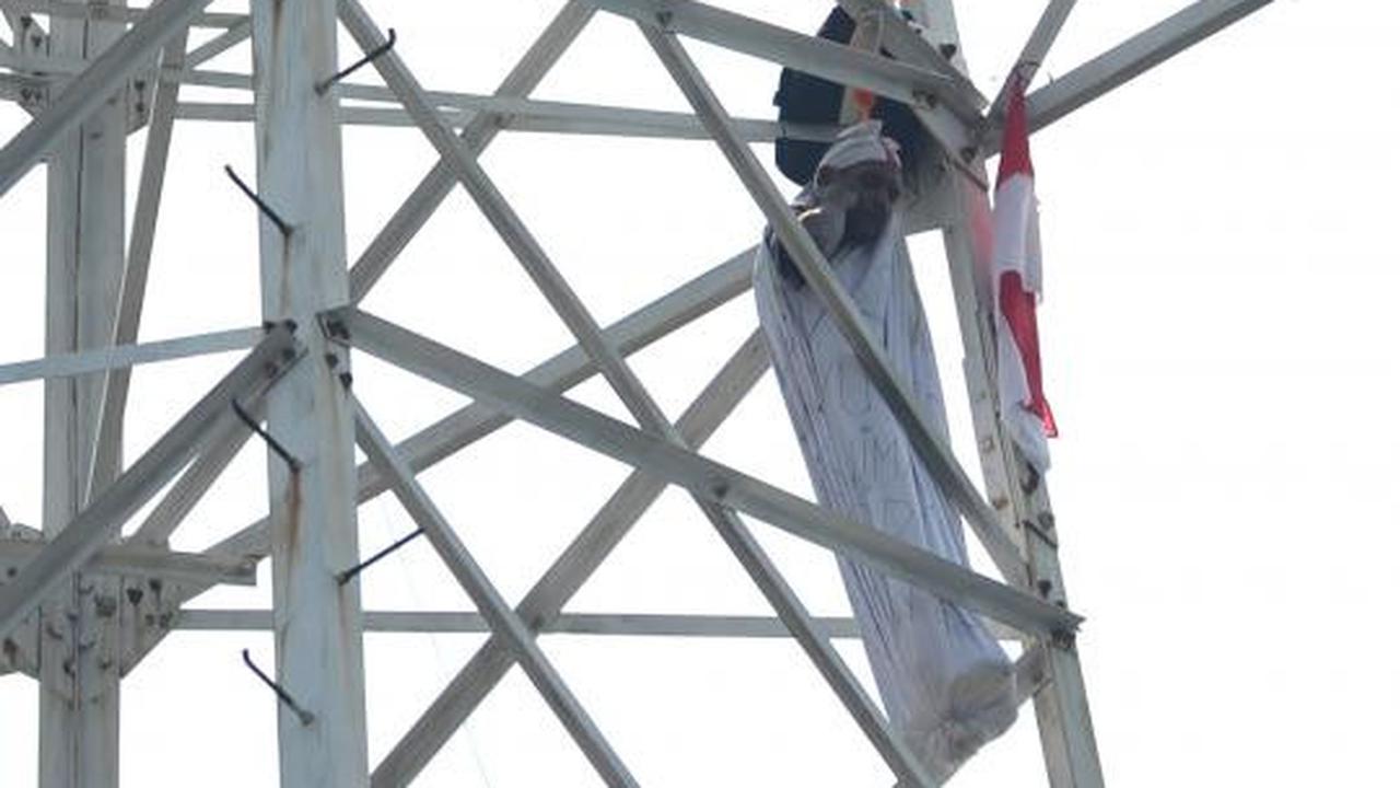 Pria berpakaian pocong di atas tower SUTET
