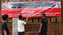 Petugas pengelola memasang spanduk pemberitahuan penutupan Kawasan Wisata Perkampungan Budaya Betawi Setu Babakan, Jakarta, Sabtu (14/3/2020). Hal ini menyusul instruksi Gubernur DKI Jakarta yang menutup sejumlah lokasi wisata selama 14 hari kedepan. (Liputan6.com/Helmi Fithriansyah)