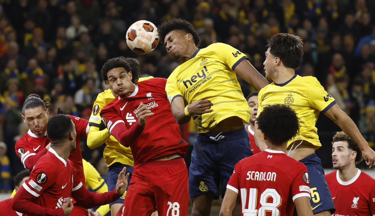 Pemain Union Saint-Gilloise, Kevin Rodriguez (tengah), berebut bola di udara dengan pemain Liverpool, Jarell Quansah, dalam laga terakhir Grup E Liga Europa 2023/2024 yang berlangsung di Lotto Park, Brussels, Jumat (15/12/2023) dini hari WIB. (AP Photo/Geert Vanden Wijngaert)